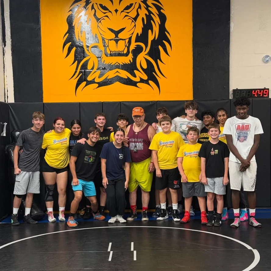 Strength coach Robert Braunstein surrounded by wrestlers celebrating his 80th birthday